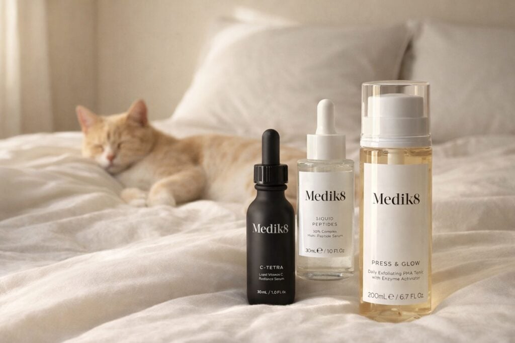 Medik8 skincare producten op een bed met een kat op de achtergrond als zachte visual voor de blog Is Medik8 Vegan
