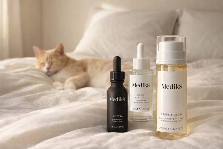 Schoonheidssalon Amsterdam 30 Medik8 skincare producten op een bed met een kat op de achtergrond als zachte visual voor de blog Is Medik8 Vegan