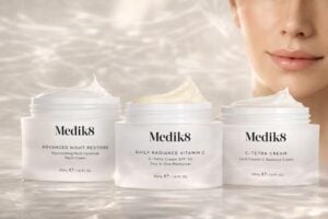 Drie Medik8 moisturizers in luxe skincare campagnebeeld: Advanced Night Restore, Daily Radiance Vitamin C en C-Tetra Cream op zachte waterreflecties met stralende huid op de achtergrond.